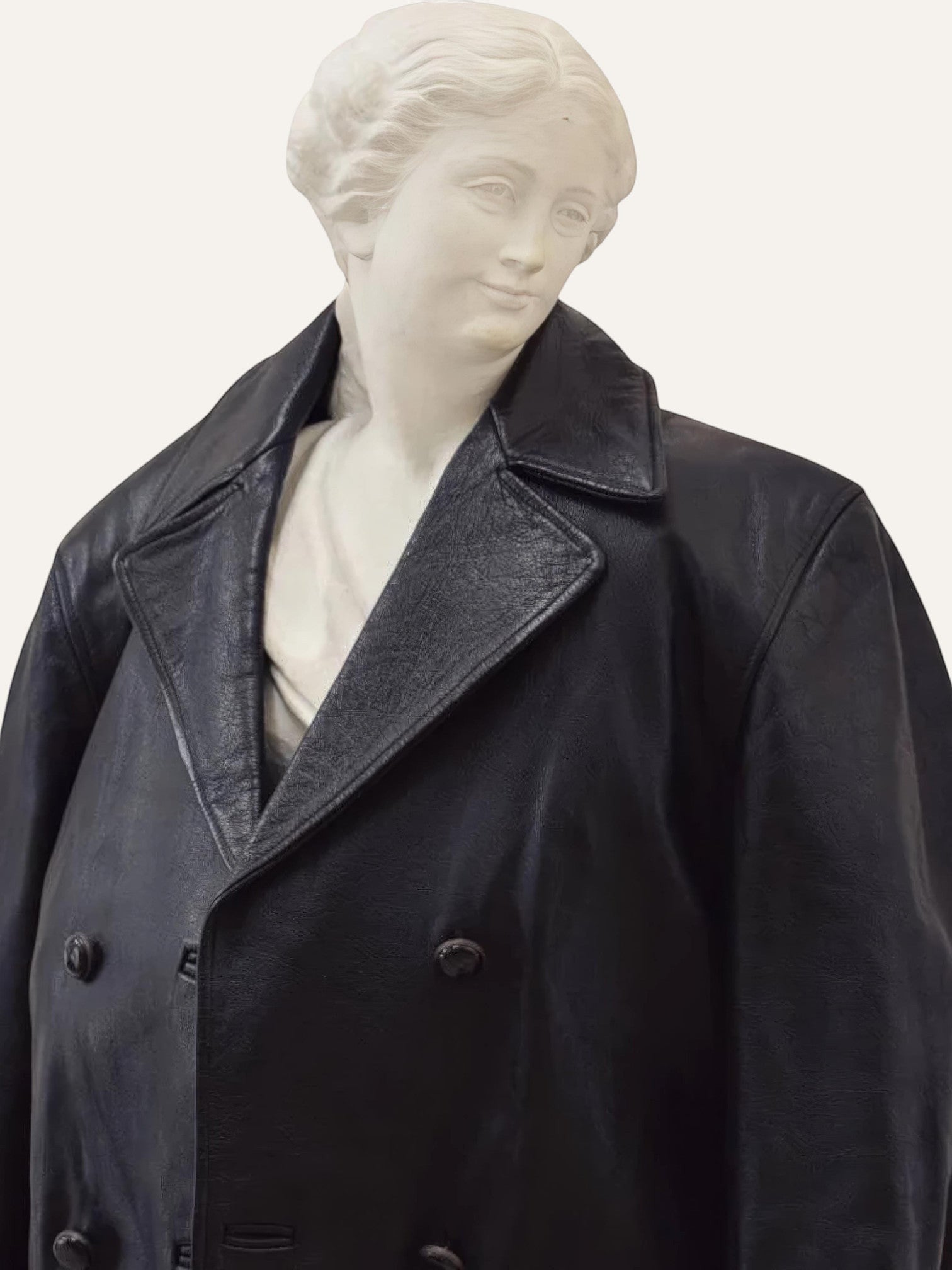Anemoia Vestiaire black genuine leather trench coat with double-breasted button closure and wide lapels, styled on a classical bust.