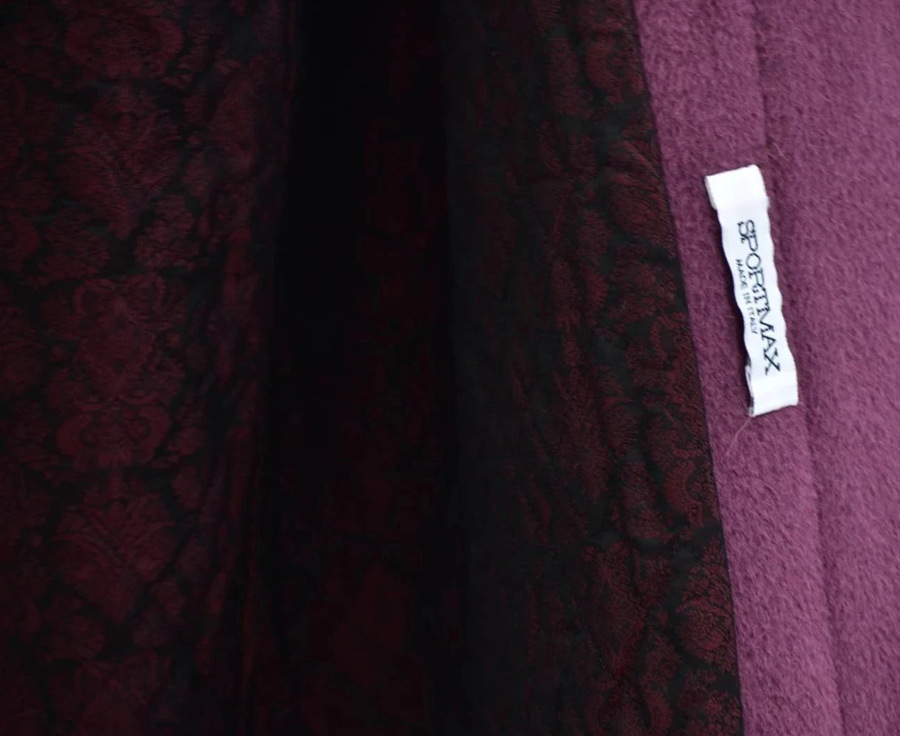 Close-up of a maroon fabric with a brand label on a blurred background