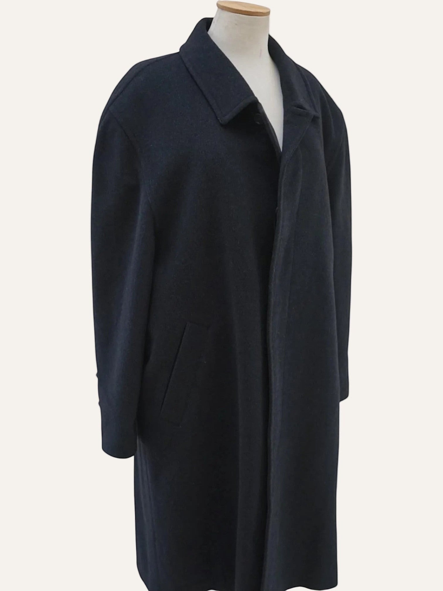 Navy blue coat on a mannequin against a white background