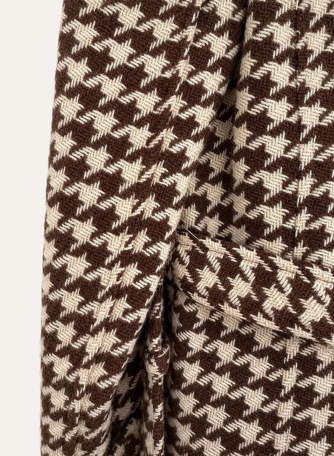 Close view of the brown and cream houndstooth weave and belted cuff